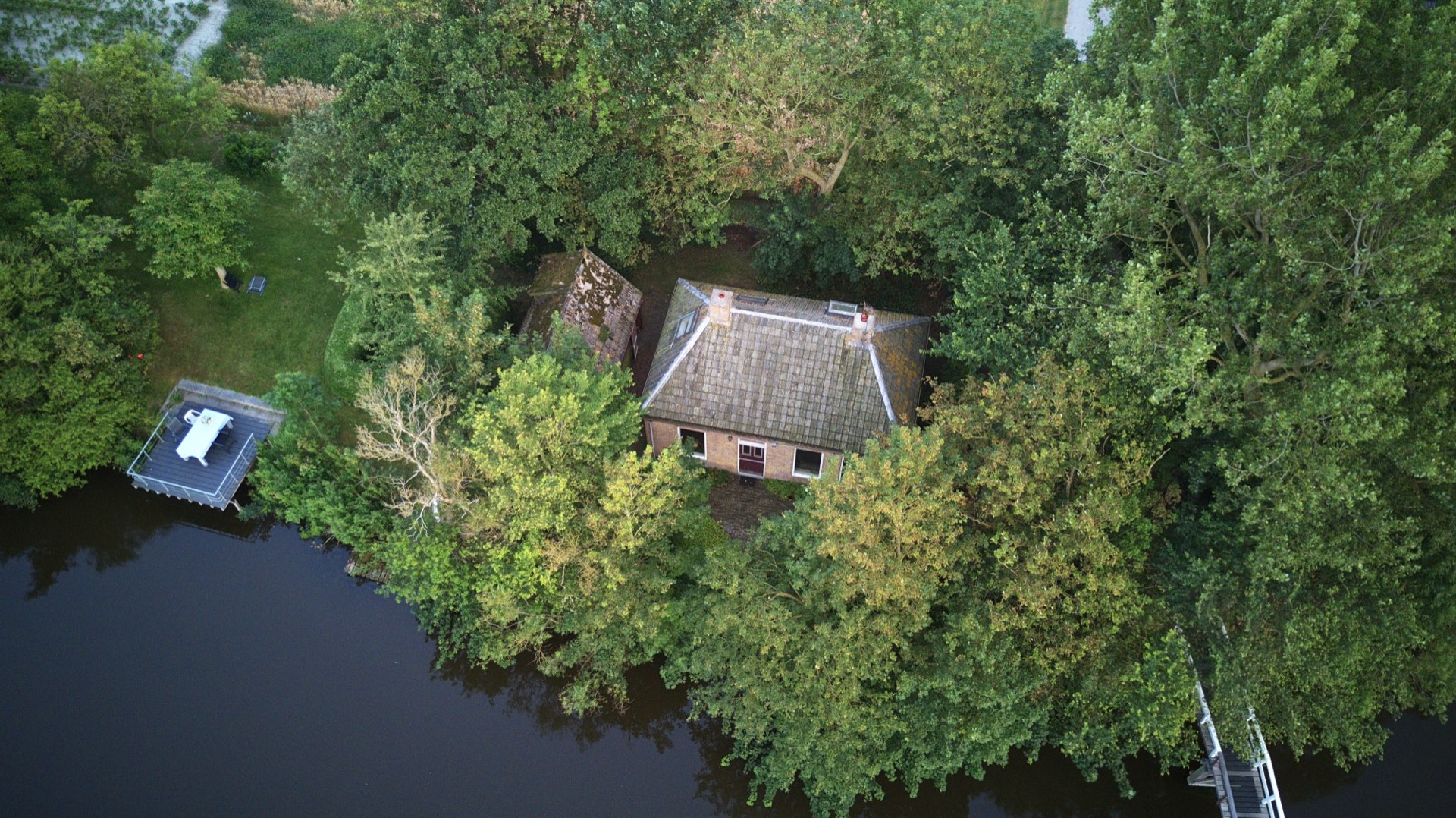 Het vissershuis tussen de bomen, met het terras aan het water