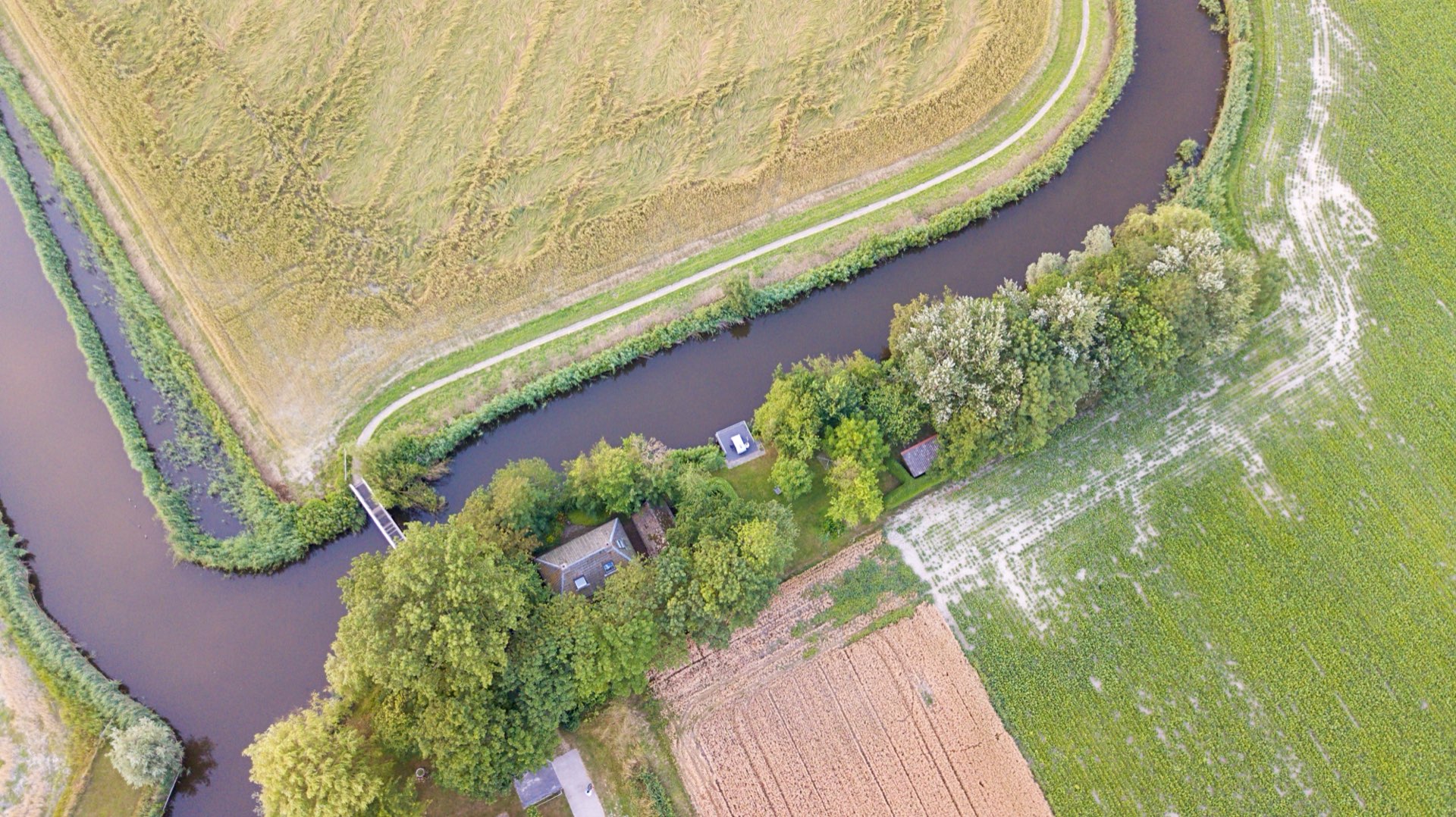 Het Elfstedenwater met de brug, langs de tuin van het huis