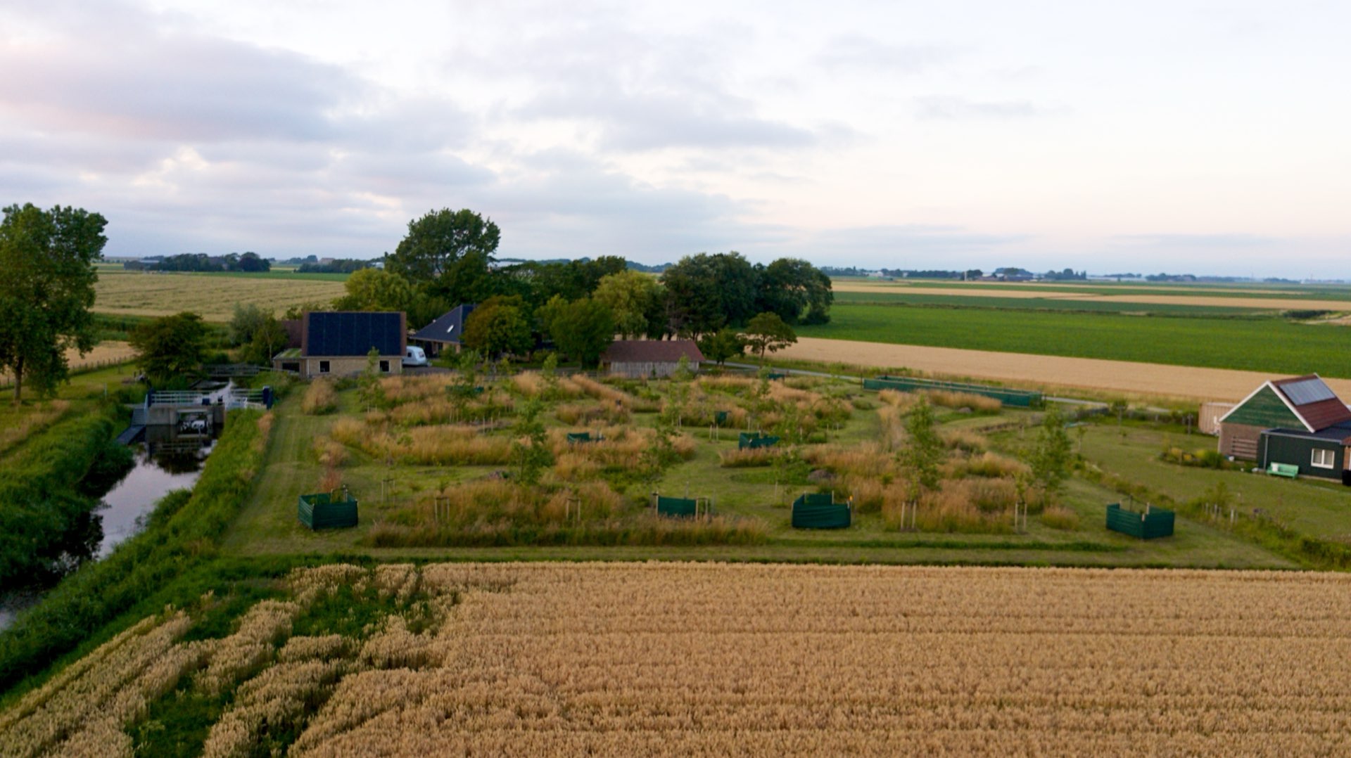 Tuinen, korenvelden en het water rond het huis, vanuit de lucht op een zomeravond