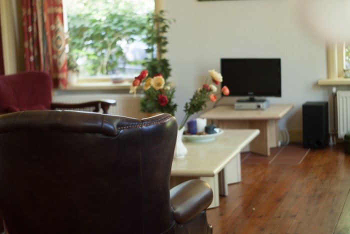 Woonkamer met leren fauteuil, salontafel en televisie