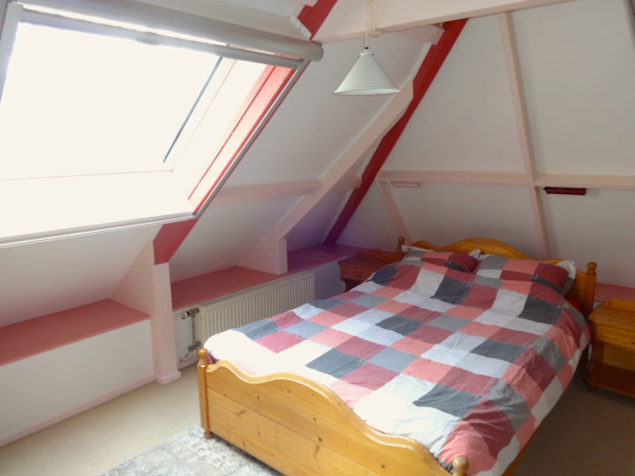 Slaapkamer onder het schuine dak met een tweepersoonsbed